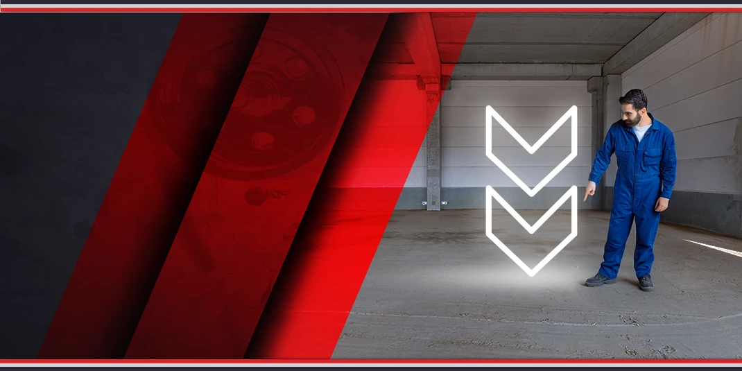 mechanik wskazujący na posadzkę warsztatu